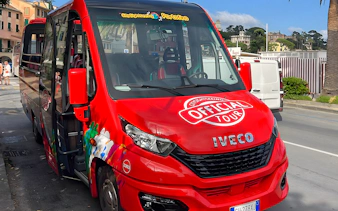 Red tour bus for day trip from Genova to Portofino parked on street.