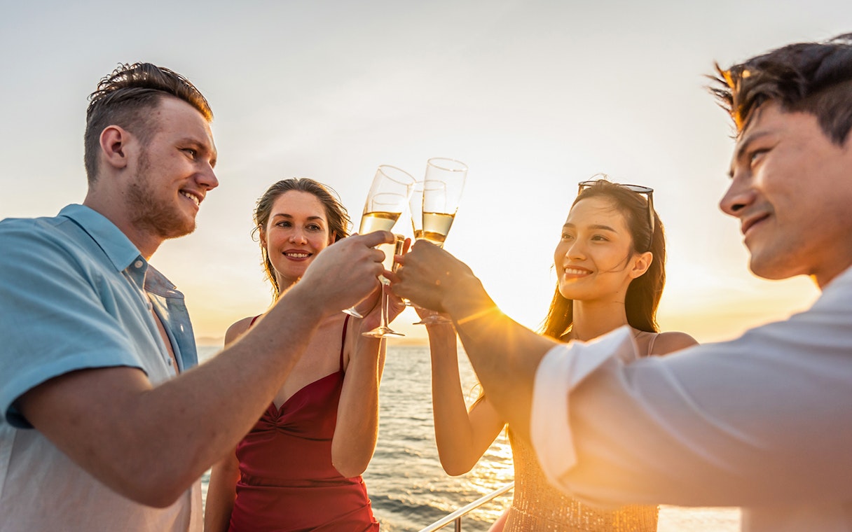 Friends toasting with drinks on a sunset cruise.