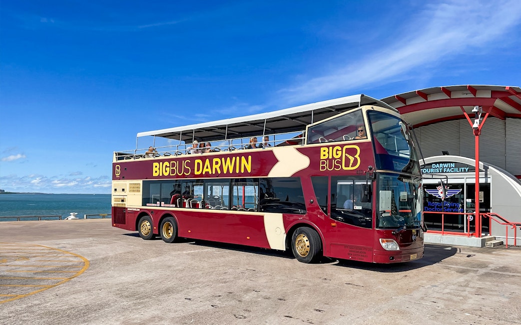 Darwin double-decker tour bus parked near waterfront and tourist facility.