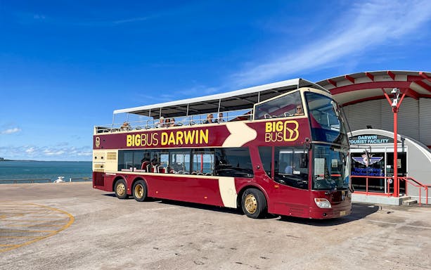 Darwin double-decker tour bus parked near waterfront and tourist facility.