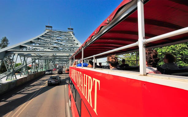 Open-top bus crossing Blue Wonder Bridge in Dresden during guided tour.