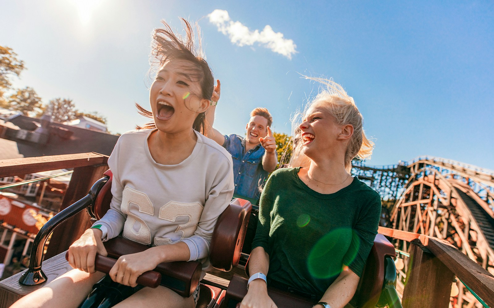 Young friends enjoying a roller coaster ride at Everland under a clear blue sky.
