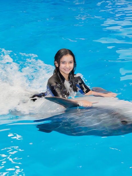 Girl swimming with a dolphin at Dubai Dolphinarium.