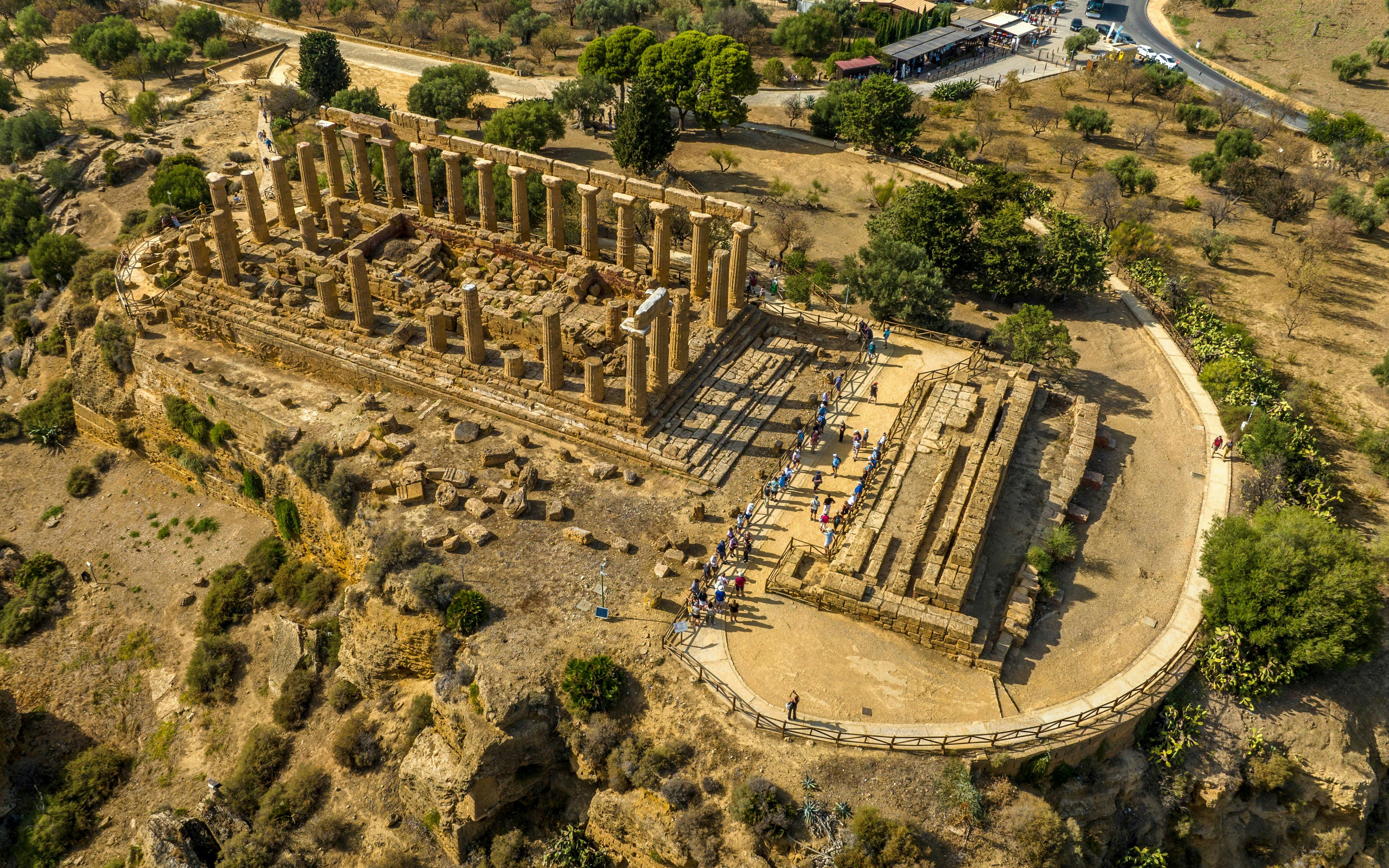 Aerial view of the Temple of Hera in Agrigento, Sicily, with tourists exploring the ancient ruins.