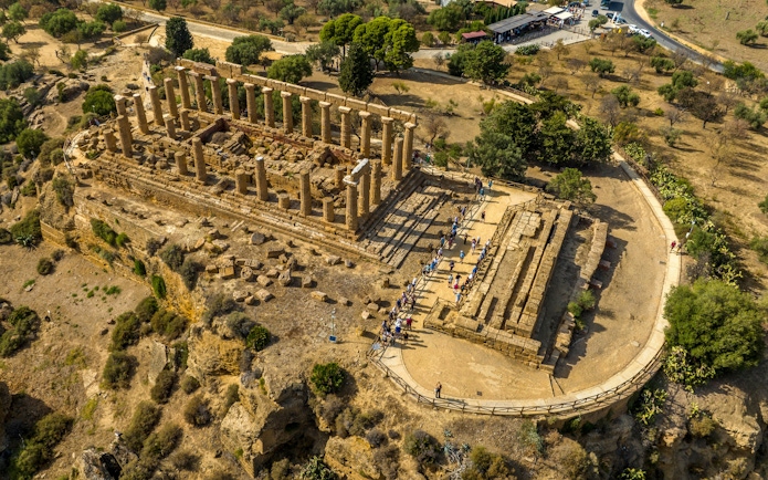 Aerial view of the Temple of Hera in Agrigento, Sicily, with tourists exploring the ancient ruins.
