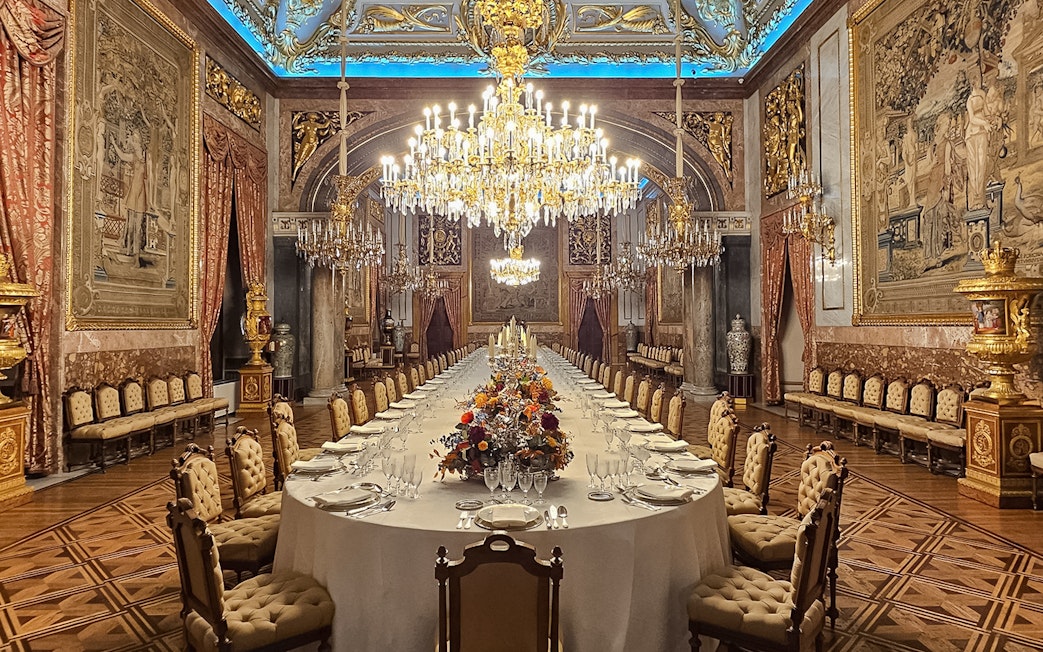 Royal Palace of Madrid dining hall with chandeliers and ornate decor.