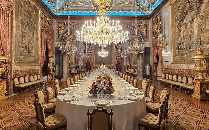 Royal Palace of Madrid dining hall with chandeliers and ornate decor.