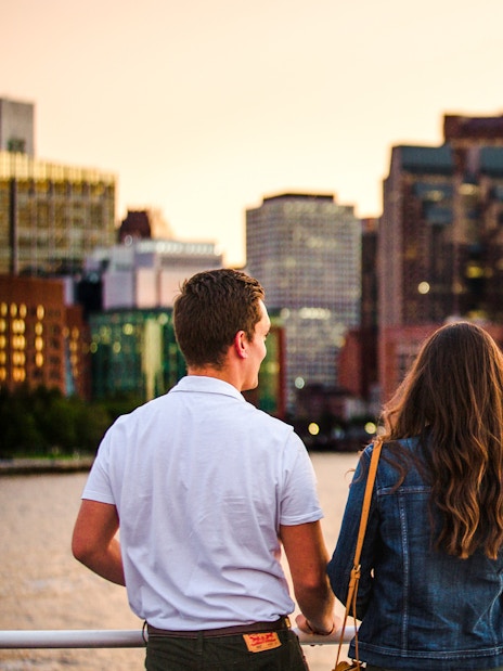 Guests enjoying a Boston sunset cruise with city skyline in the background.