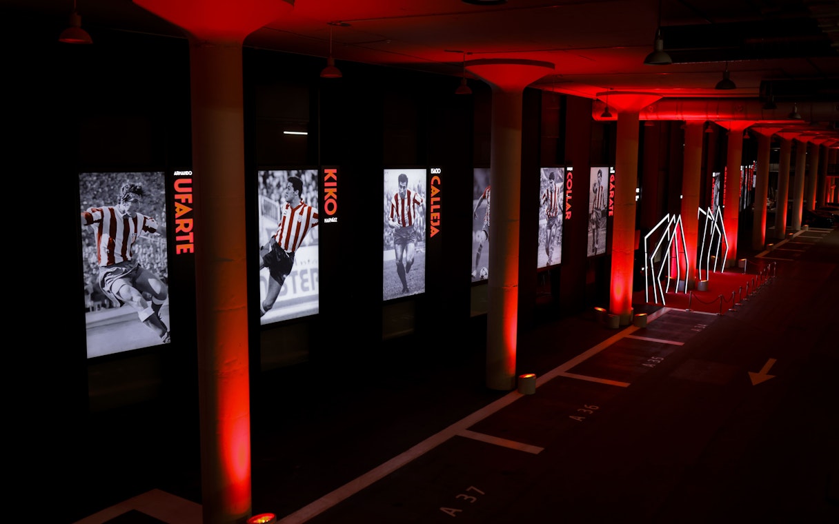 Atlético de Madrid museum hallway with player exhibits and red lighting.