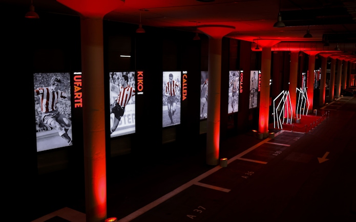 Atlético de Madrid museum hallway with player exhibits and red lighting.