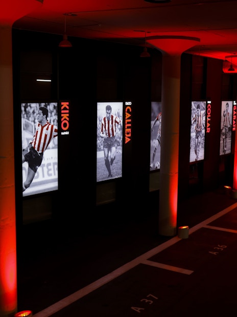 Atlético de Madrid museum hallway with player exhibits and red lighting.
