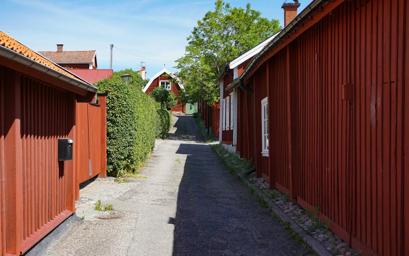 Narrow cobblestone street with red wooden houses in Stockholm.
