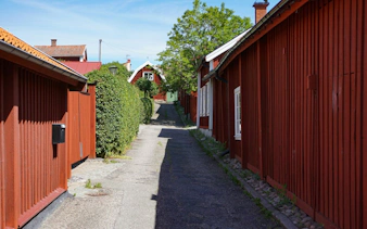Narrow cobblestone street with red wooden houses in Stockholm.