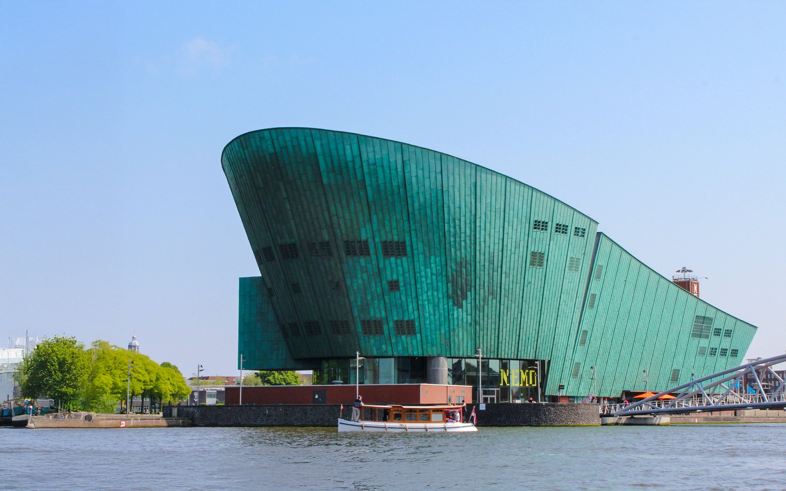 NEMO Science Museum's green copper exterior with canal view in Amsterdam.