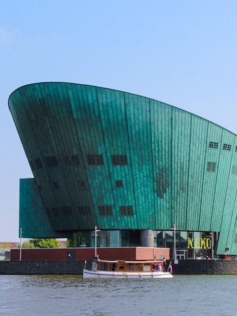 NEMO Science Museum's green copper exterior with canal view in Amsterdam.