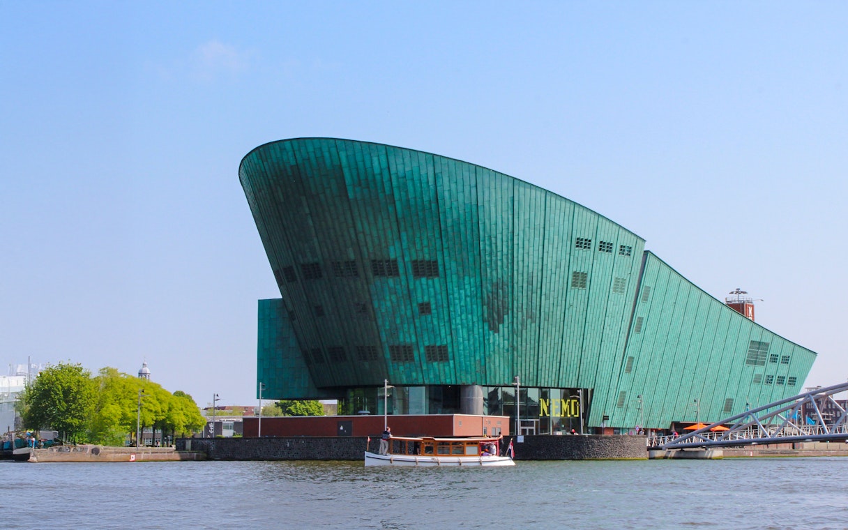 NEMO Science Museum's green copper exterior with canal view in Amsterdam.