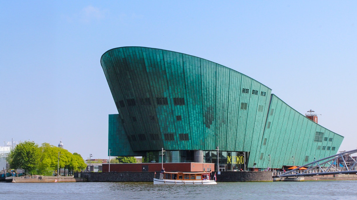 NEMO Science Museum's green copper exterior with canal view in Amsterdam.