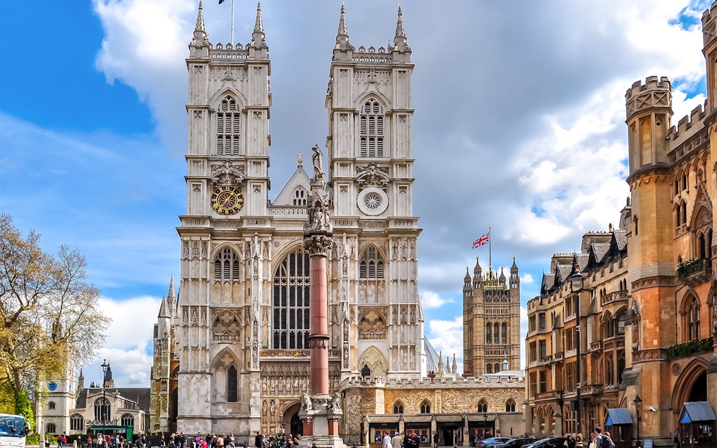 Westminster Abbey facade with clock tower and surrounding buildings, London.