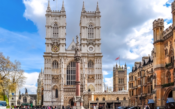 Westminster Abbey facade with clock tower and surrounding buildings, London.