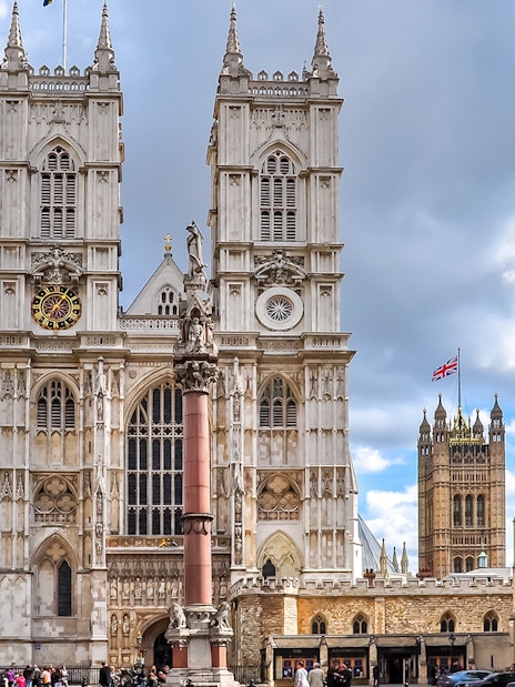 Westminster Abbey facade with clock tower and surrounding buildings, London.