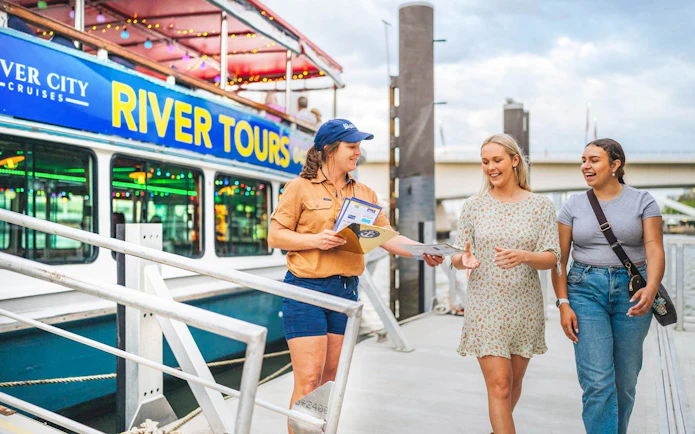 River City Cruises staff member gives tour information to guests at Brisbane dock.