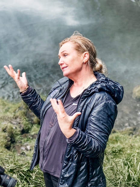Two people discussing near a waterfall on the Glacier Lagoon & South Iceland Tour.