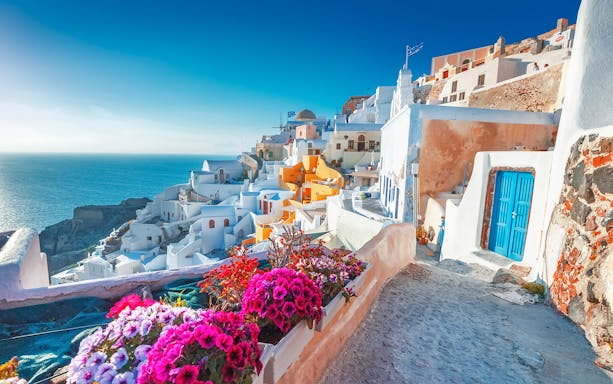 Santorini whitewashed buildings with blue doors overlooking the Aegean Sea.