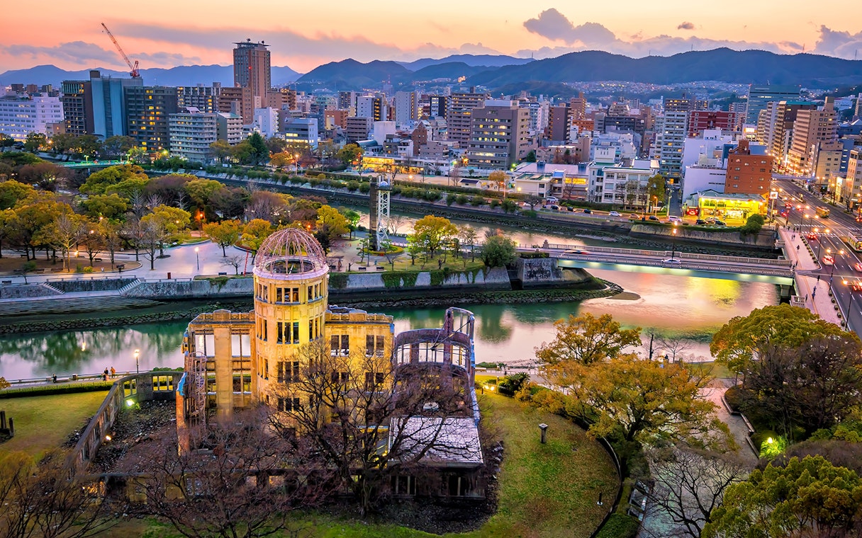 Aerial view of Hiroshima Peace Memorial and cityscape at sunset.