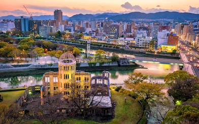 Aerial view of Hiroshima Peace Memorial and cityscape at sunset.