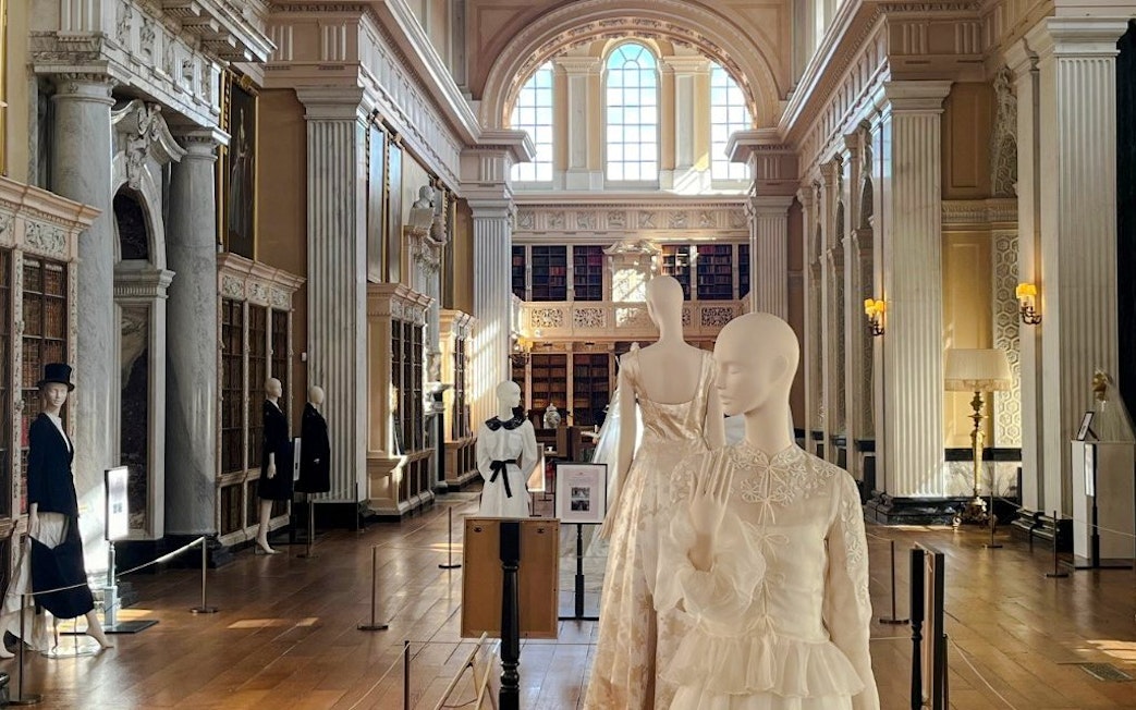 Mannequins in elegant attire displayed in the grand library of Blenheim Palace.