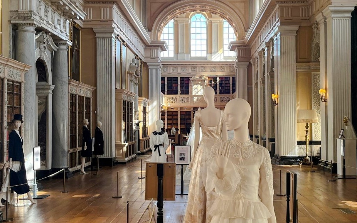 Mannequins in elegant attire displayed in the grand library of Blenheim Palace.