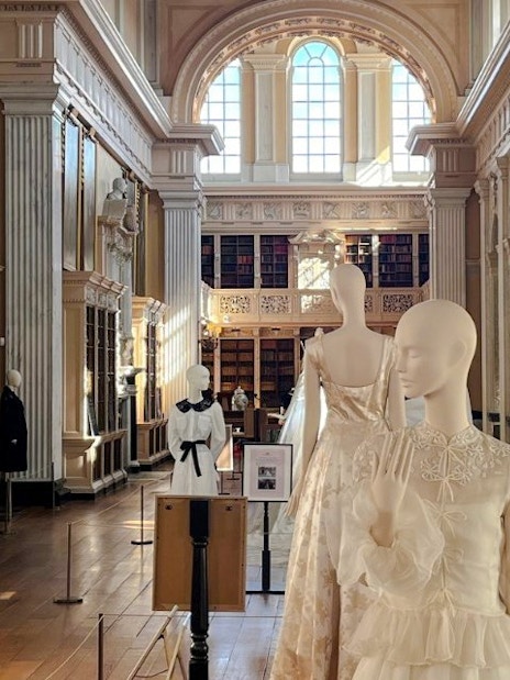 Mannequins in elegant attire displayed in the grand library of Blenheim Palace.
