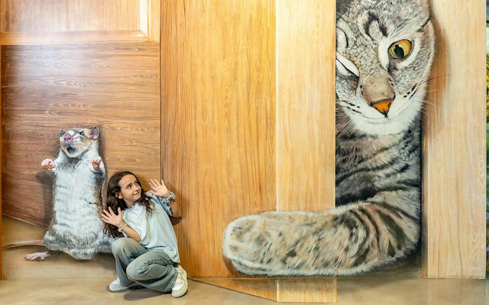 Child posing with 3D cat and mouse art at Big Fun Museum, Barcelona.