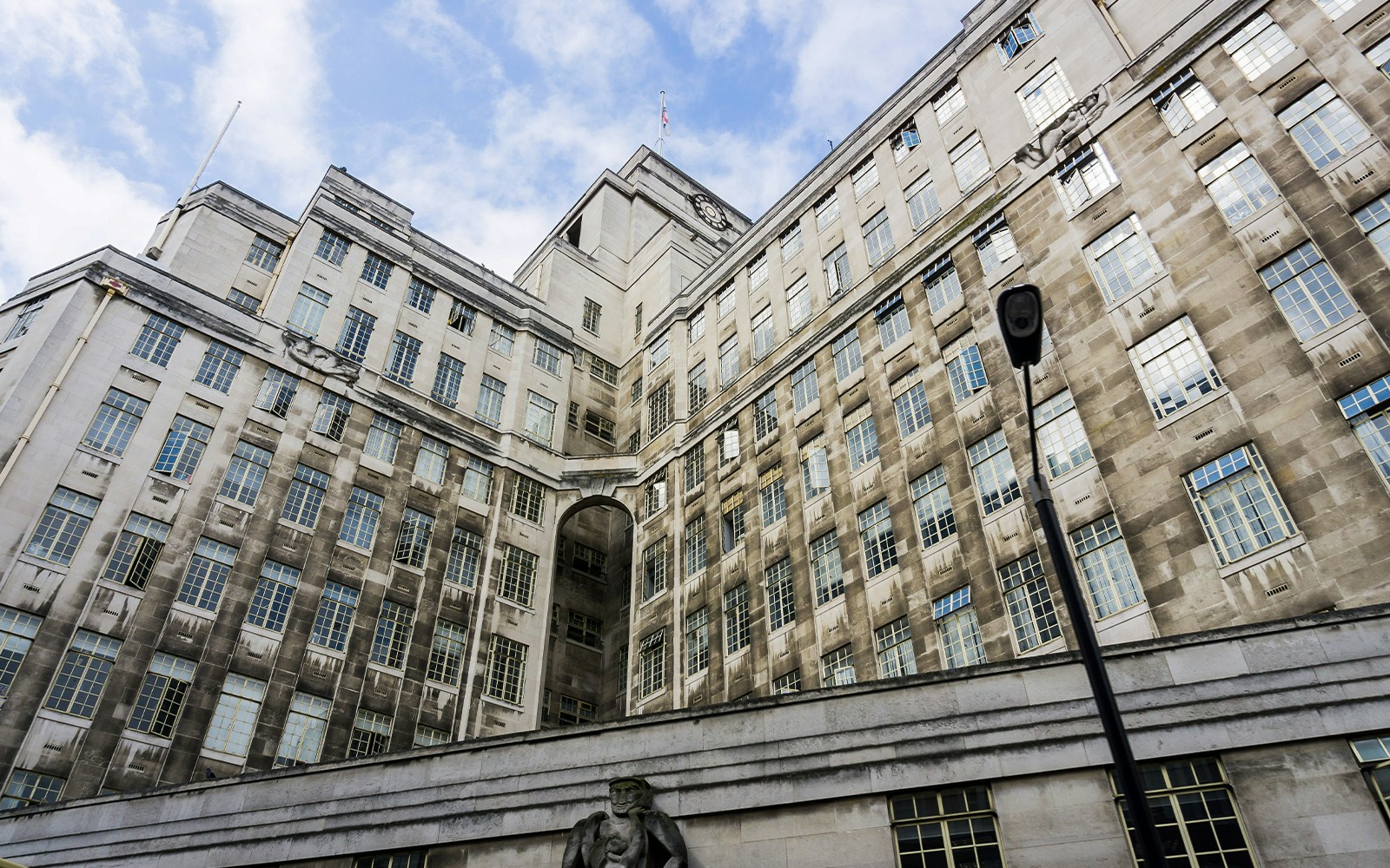 Historic stone building with large windows and a clock tower under a blue sky.