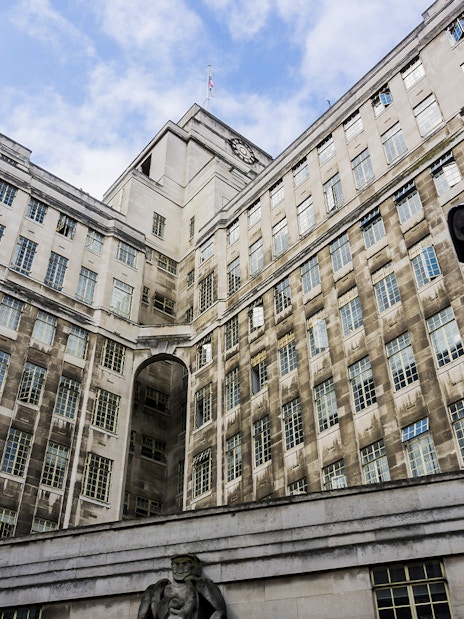 Historic stone building with large windows and a clock tower under a blue sky.