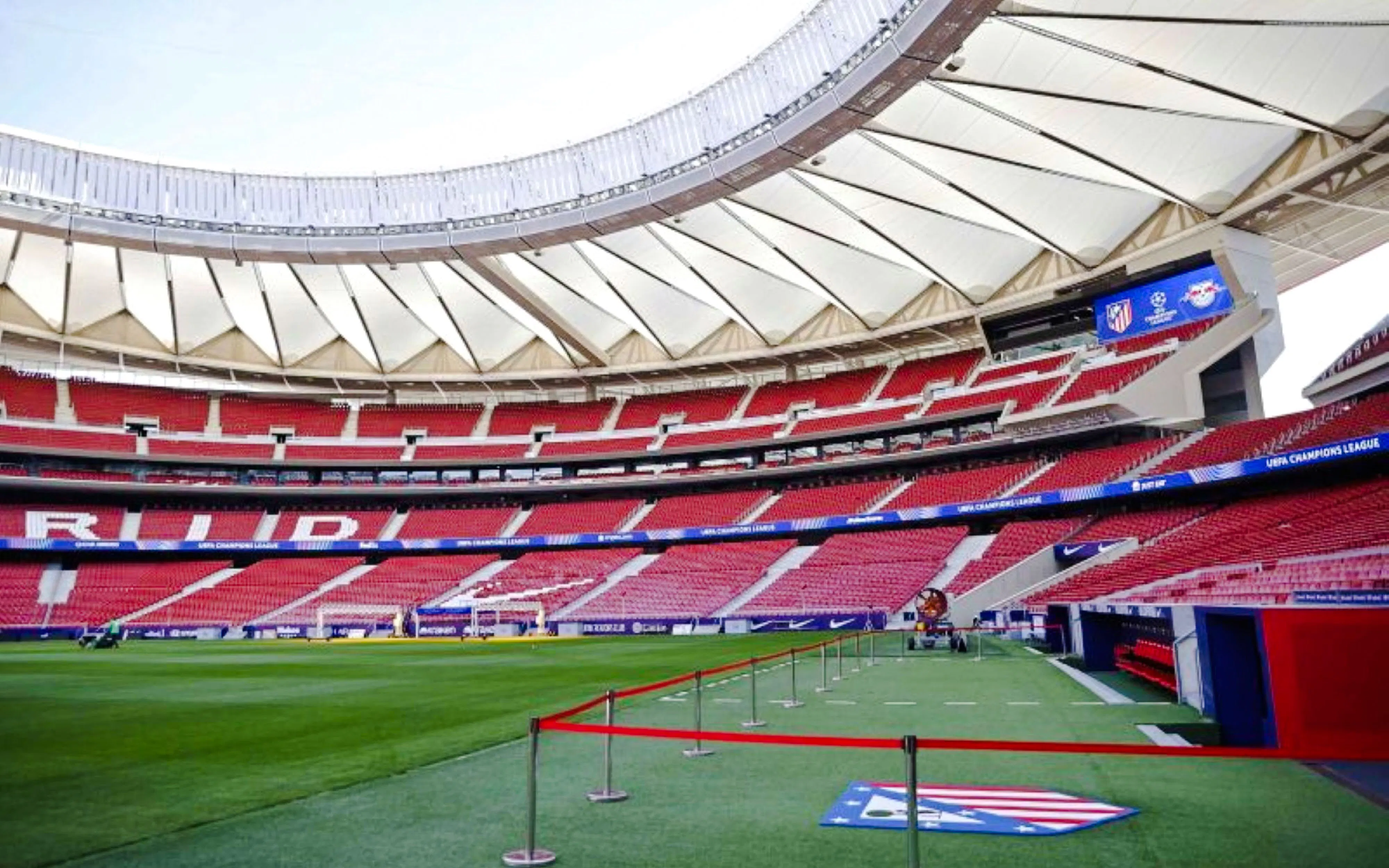 Atletico Madrid stadium interior with red seats and green field.