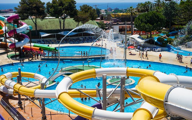 Water slides and pools at Illa Fantasia Water Park, Barcelona, with visitors enjoying the attractions.