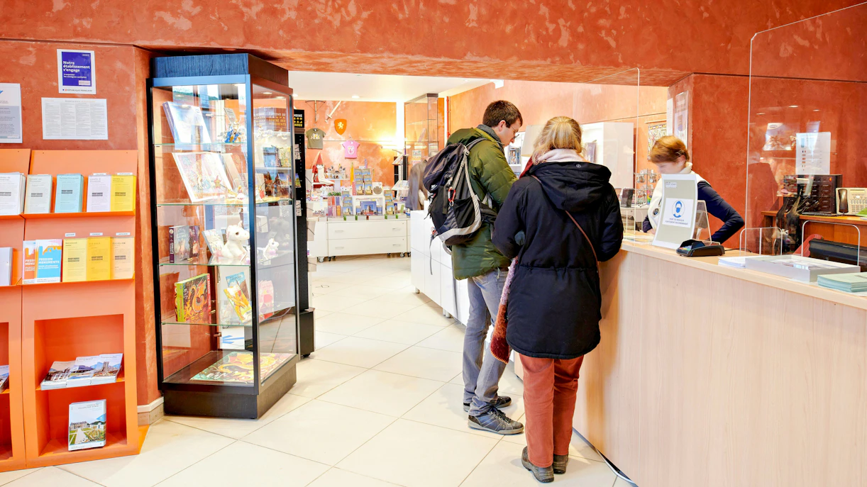 Visitors at a counter in a Vincennes bookshop, browsing books and brochures.
