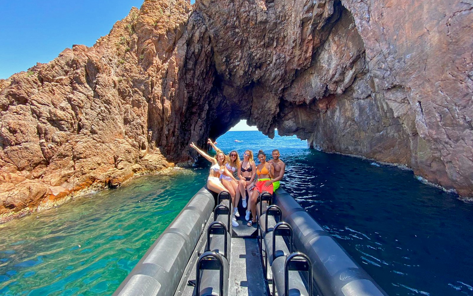 Boat tour group exploring rocky arch in Estérel Natural Park, Cannes.