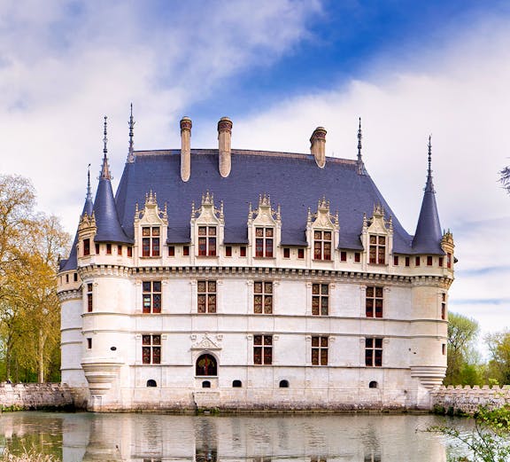 Loire Valley castle with moat and spires under a blue sky.