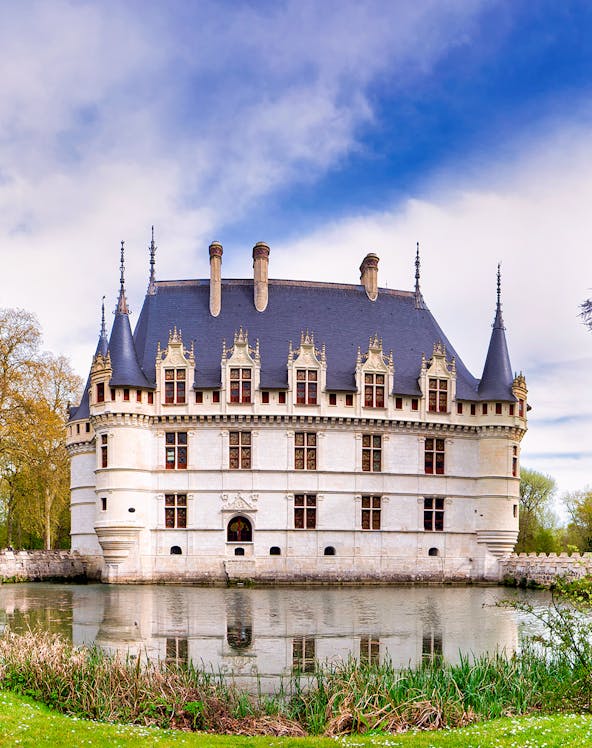 Loire Valley castle with moat and spires under a blue sky.