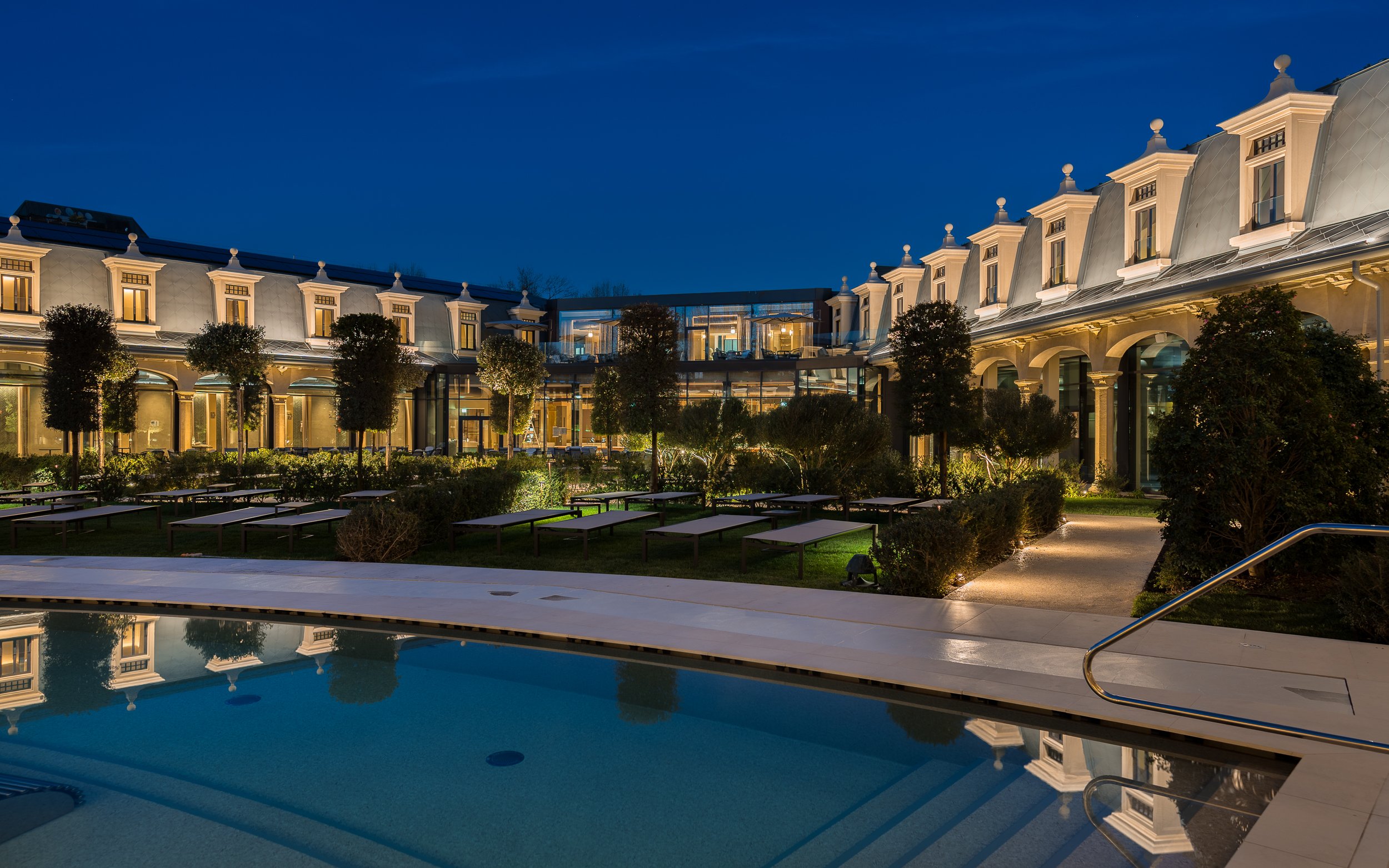 Panoramic night view of Milan Wellness Spa with illuminated pool and garden.