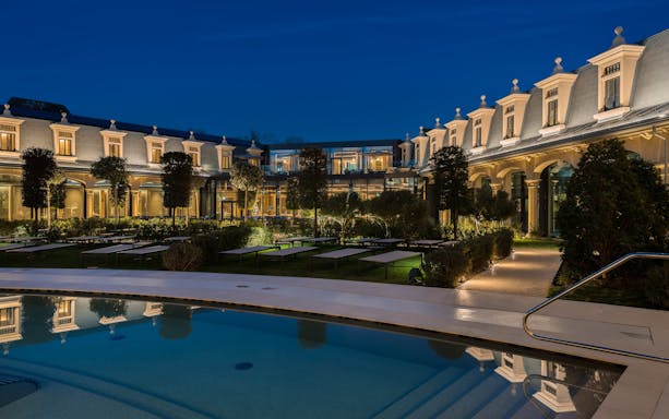 Panoramic night view of Milan Wellness Spa with illuminated pool and garden.