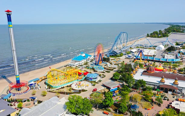 Cedar Point Boardwalk with roller coasters, Ferris wheel, and lakeside view.