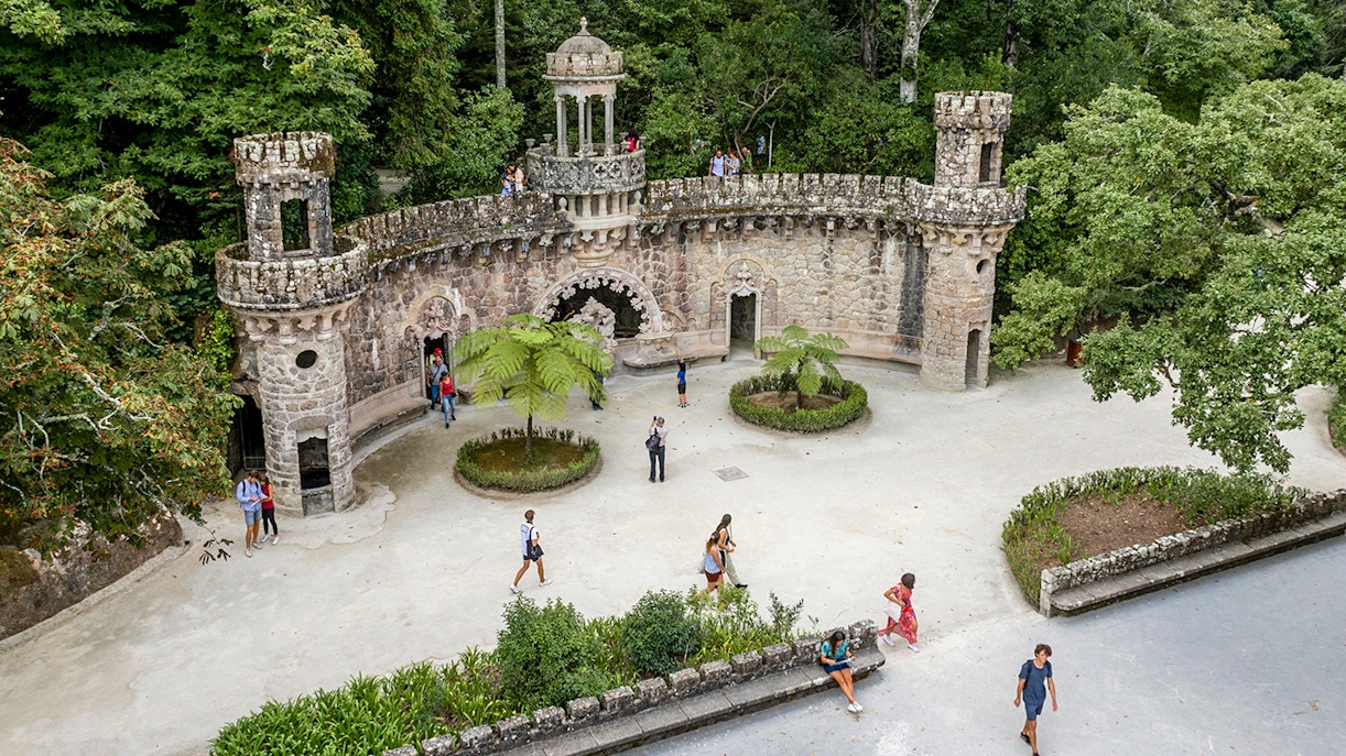 Guided tour group exploring gardens at Quinta da Regaleira, Sintra.