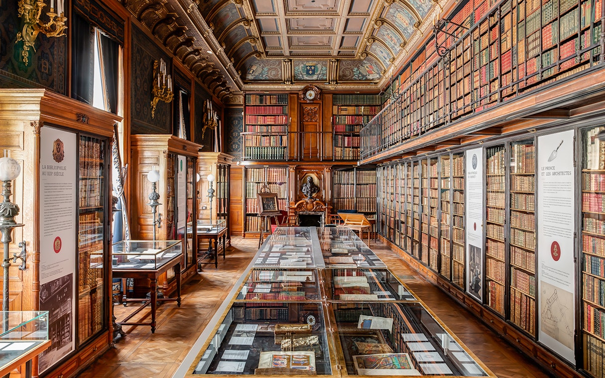 Chateau of Chantilly library interior with ornate ceiling and book displays.
