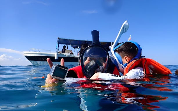 Snorkelers in life vests near a boat during Semporna day tour at Mataking Island.