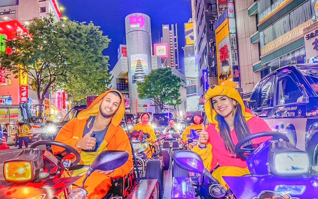 Go-kart parade in Shinjuku, Tokyo with participants in colorful costumes.