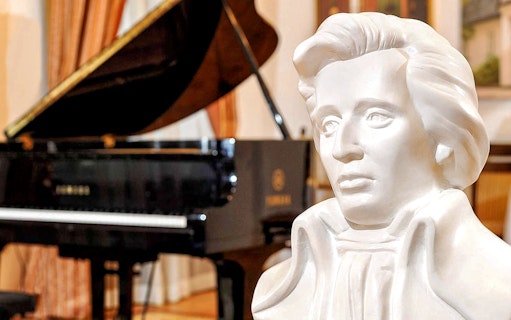 Bust of composer with grand piano in background at Chopin Piano Concert.