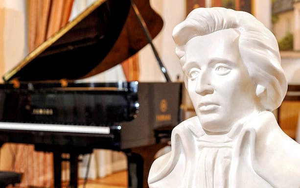 Bust of composer with grand piano in background at Chopin Piano Concert.